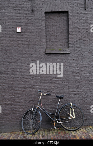 Un tradizionale bicicletta olandese appoggia contro un muro di mattoni in Amsterdam, Paesi Bassi. Foto Stock