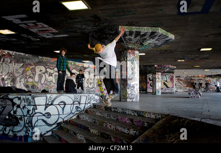 Un guidatore di skateboard eseguendo uno stunt al undercroft sulla banca del sud. Foto Stock