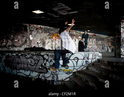 Un guidatore di skateboard eseguendo uno stunt al undercroft sulla banca del sud. Foto Stock