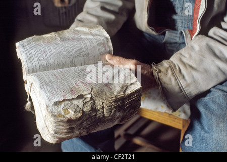 Il vecchio uomo di mani molto usurati famiglia la bibbia con fatti passare cerchiato in inchiostro rosso Foto Stock