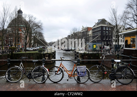 Biciclette appoggiata contro le ringhiere su un ponte sul canale di Amsterdam, Paesi Bassi. Foto Stock