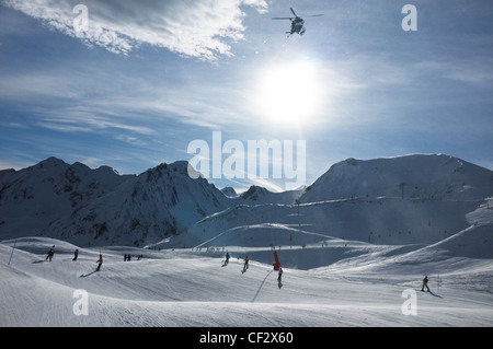 Un elicottero decolla oltre gli sciatori a Peyragudes ski resort, Midi-Pirenei, Francia. Foto Stock