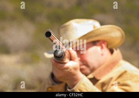 Uomo anziano con il cappello da cowboy fucile da caccia di ripresa Foto Stock