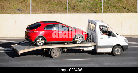 Bianco raccoglitore non marcati autocarro autocarro auto transporter caricato con auto rossa percorrendo l autostrada M25, Essex England Regno Unito Foto Stock