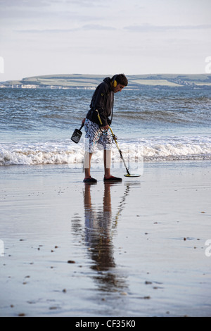 Un uomo di rilevamento di metallo sulla riva del mare a Bournemouth. Foto Stock