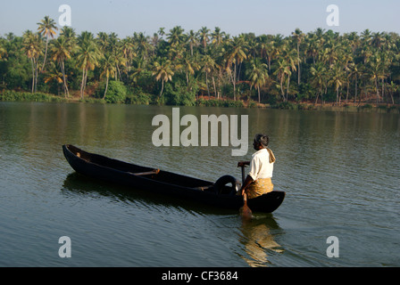 Uomo in barca a vela attraverso le lagune del Kerala.vista panoramica di piccola canoa barca in Kerala backwaters e sullo sfondo di un paesaggio Foto Stock