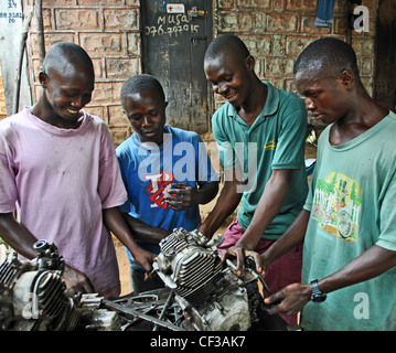 Moto meccanica e i loro apprendisti lavorare su un motore in un workshop in Bo, Sierra Leone Foto Stock