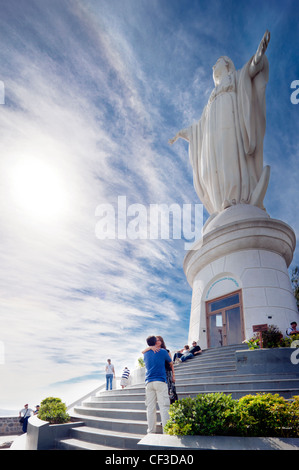 Santiago del Cile, Cerro San Cristobal Hill. Felice coppia baciare sotto il famoso punto di riferimento la Beata Vergine Maria in primavera. Foto Stock