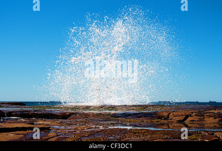 Grande splash come un onda colpisce le rocce lungo la costa Foto Stock