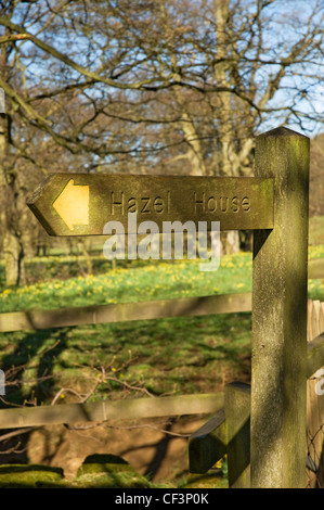 Un cartello in legno di nocciolo casa vicino Chiesa Case villaggio. Foto Stock