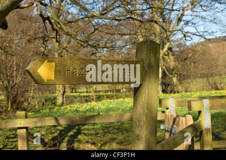 Un cartello in legno di nocciolo casa vicino Chiesa Case villaggio. Foto Stock