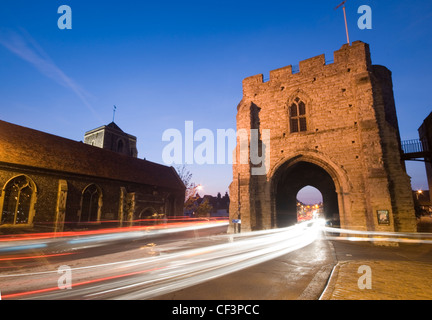 La Torre Westgate in Canterbury illuminata di notte con prove di luce dal traffico in transito. Foto Stock