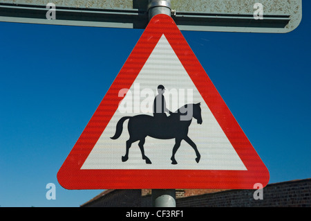 Un triangolo rosso cartello di avviso per informare che ha accompagnato i cavalli e pony utilizzare la strada. Foto Stock