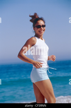 Semi di profilo ondulato femmina brunette capelli viso off indossando occhiali da sole tartaruga, bianco Gilet top blu e hot pants, Foto Stock