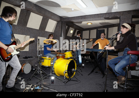 Una rock band. Il cantante ragazza, due musicisti con electro chitarre, tastierista e un batterista che lavorano in studio. lampeggia in centro Foto Stock