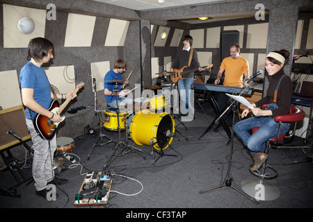 Una rock band. Il cantante ragazza, due musicisti con electro chitarre, tastierista e un batterista che lavorano in studio Foto Stock