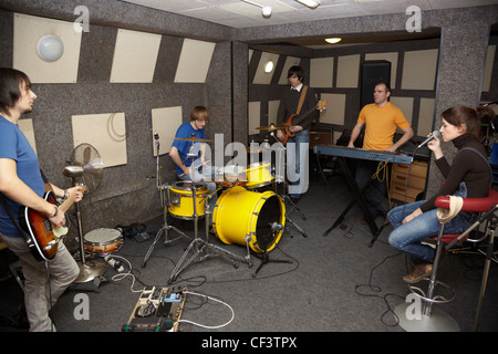 Un riflessivo rock band. triste cantante ragazza, due musicisti con electro chitarre e un batterista che lavorano in studio. Foto Stock