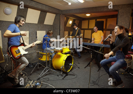 Una rock band cantante ragazza due musicisti elettro chitarre tastierista un batterista a lavorare in studio di gioia creazione Foto Stock