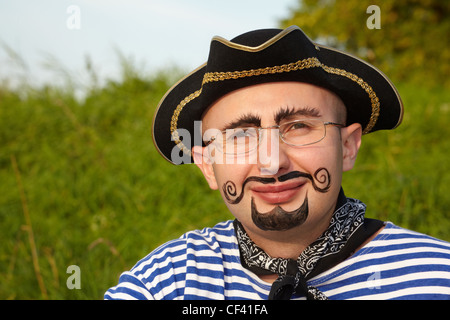 Ritratto di uomo sorridente con disegnò la barba e baffi in tuta pirata in inizio di caduta sera park Foto Stock
