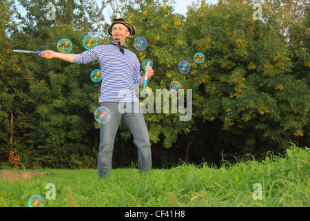 Uomo con disegnò la barba e baffi in tuta pirata soffia bolle di sapone. Foto Stock