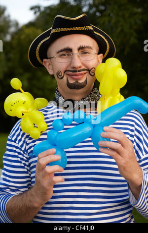 Uomo sorridente con disegnò la barba e baffi in tuta pirata con tre aria-ballons Foto Stock