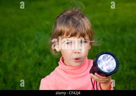 Ragazza che gioca con la lanterna. Ritratto di una ragazza contro un'erba. sfondo di erba Foto Stock