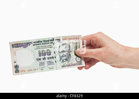 Un indiano 100 rupie bill con il ritratto del Mahatma Gandhi è tenuto in mano, sfondo bianco. Foto Stock