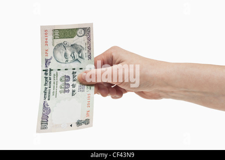 Un indiano 100 rupie bill con il ritratto del Mahatma Gandhi è tenuto in mano, sfondo bianco. Foto Stock