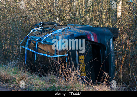 Auto ribaltata in un fosso dopo e incidente stradale scontro del veicolo Foto Stock