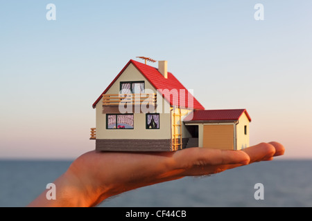 Modello di casa con garage a portata di mano contro il mare Foto Stock