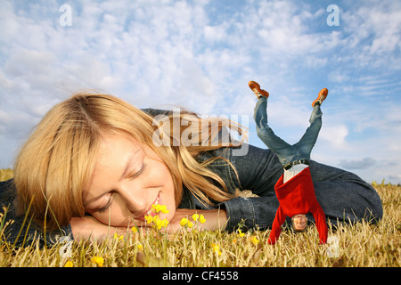 Giovane donna si trova sull'erba e ragazzo in miniatura su mani collage Foto Stock