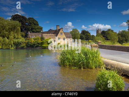 Guardando attraverso l'acqua al mulino a Fairford, nel Gloucestershire. Foto Stock