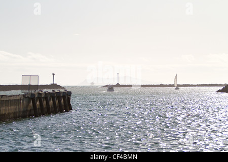 Una barca che lasciano il canale Island Harbour in Oxnard in California con Isola di Santa Cruz una delle Isole del Canale e di un impianto di trivellazione petrolifera Foto Stock