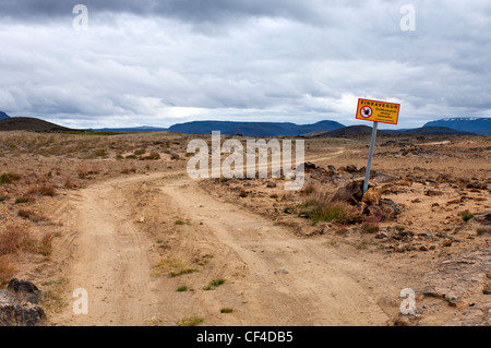 Segnale di avvertimento adiacente ad un avvolgimento di strada sterrata nel paesaggio arido e tundra di Islanda Foto Stock
