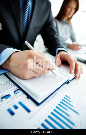 Immagine del lato maschio con la penna sulla pagina del notebook al seminario Foto Stock