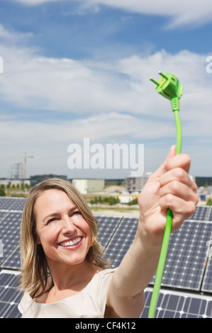 Germania - Monaco, Donna tenendo il cavo elettrico in energia solare, sorridente Foto Stock