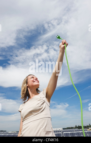 Germania - Monaco, Donna tenendo il cavo elettrico in energia solare, sorridente Foto Stock