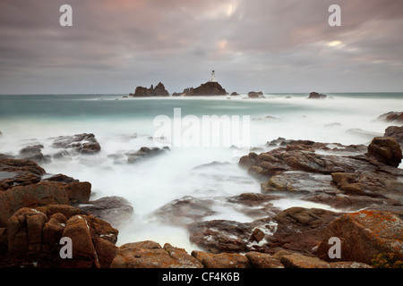 Mare mosso circa la Corbiere Lighthouse al tramonto. Il faro è stato il primo nelle isole britanniche per essere costruito da calcestruzzo. Foto Stock