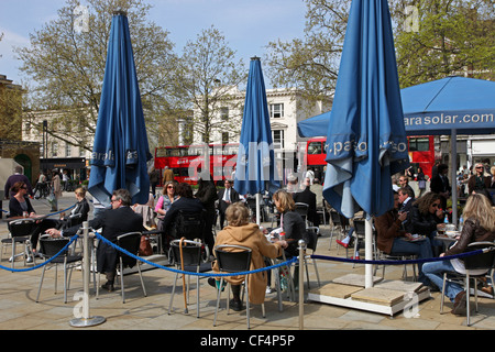 La gente seduta ai tavoli in un cafe' sul marciapiede sul King's Road nel quartiere di Chelsea. Foto Stock