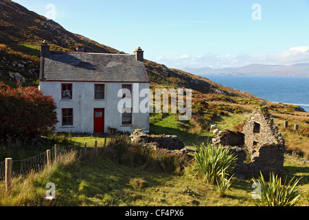 Abbandonato tradizionale del XIX secolo agriturismo irlandese, una volta casa di artista John Kingerlee, accanto a un vecchio rovinato cottage sul Foto Stock