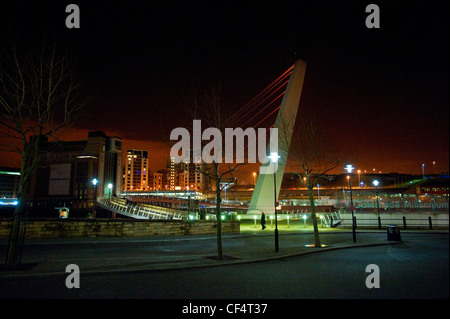 Un uomo che cammina verso il Gateshead Millennium Bridge sul fiume Tyne verso il Baltico Centro per l arte contemporanea sul Foto Stock