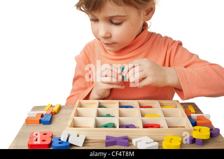 Graziosa bambina visualizza figure in legno in forma di numeri sul tavolo isolato su sfondo bianco Foto Stock