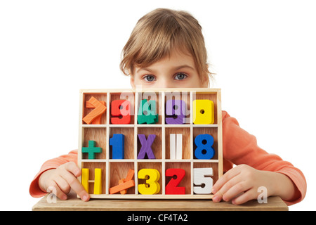 Graziosa bambina gioca nelle figure in legno in forma di numeri isolati su sfondo bianco Foto Stock