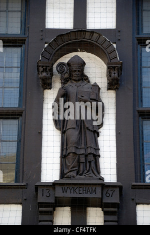 Statua di William di Wykeham, Vescovo di Winchester sulla parte esterna di un edificio Tudor in Winchester High Street. Foto Stock