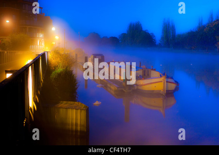 Una casa galleggiante ormeggiata presso un molo sul Fiume Tamigi su una mattinata nebbiosa. Foto Stock
