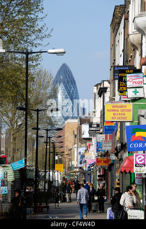 Una vista lungo Whitechapel Road verso il Gherkin (Swiss Re Building) nella città di Londra in distanza. Foto Stock