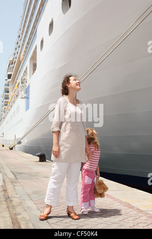 Giovane madre e figlia in piedi in dock vicino al grande nave da crociera e guardando su di esso Foto Stock