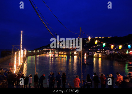 Foto di persone che guardano il Mousehole, Cornwall le luci di Natale. Una piccola quantità di rumore a causa della esposizione al buio. Foto Stock