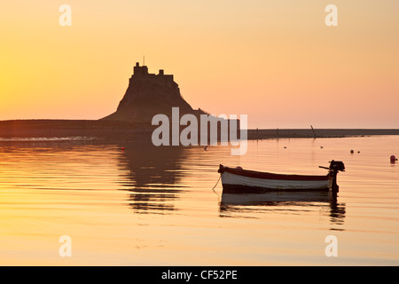 Una piccola barca ormeggiata presso Lindisfarne Castle all'alba. Foto Stock