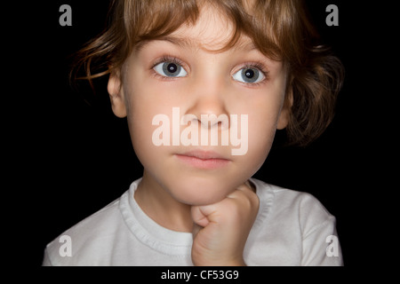 Premurosa bambina in bianco T-shirts isolati su sfondo nero Foto Stock